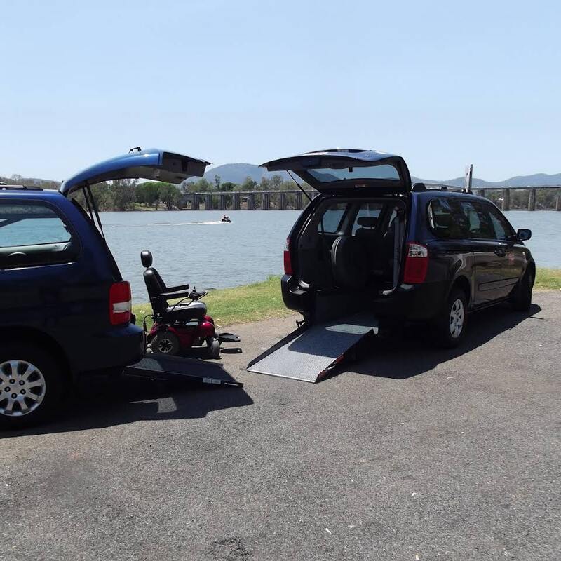 two mobility vans with ramps down and an electric wheelchair parked beside the fitzroy river rockhampton